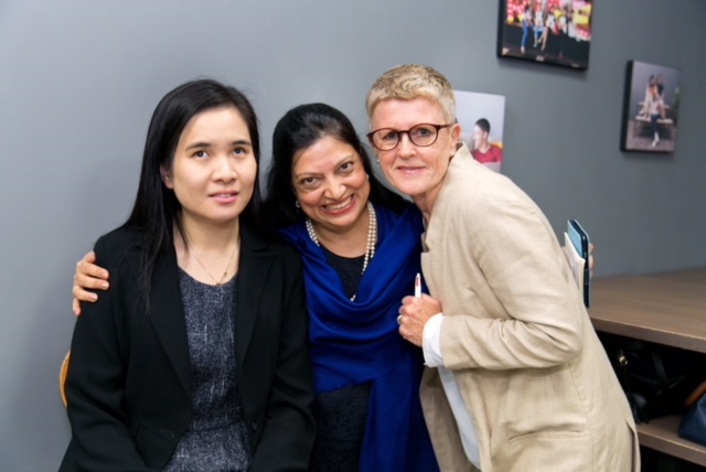 3 women in business attire are posing for a group photo