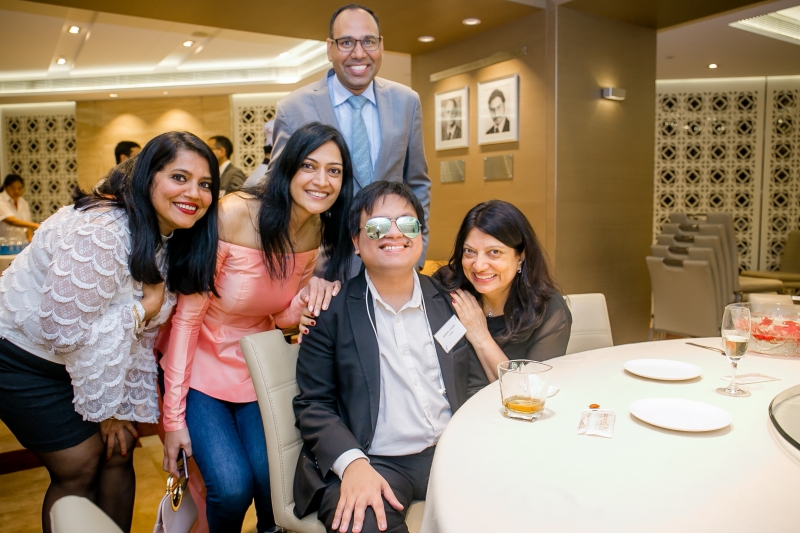 Faride Shroff with visually impaired musician seated at a table with 2 women and a man around him.
