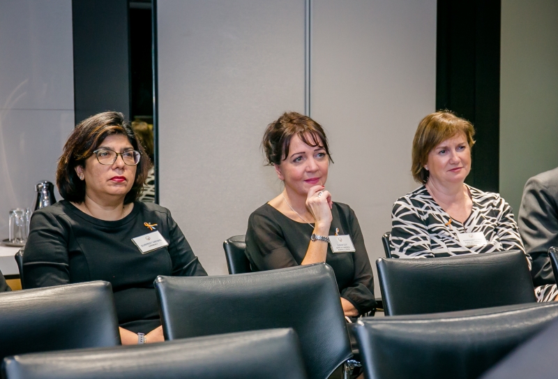 3 women in business attire sitting at the back row of the audience seating