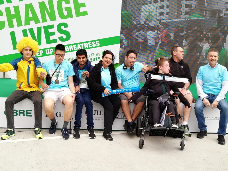 a group of differently abled individuals pose in front of an event backdrop