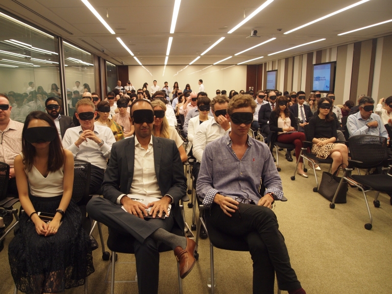 blindfolded participants sit in a conference room